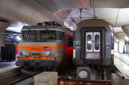 Foto de París, Francia - enero de 2021 - Un motor de tren Alsthom fabricado en la década de 1980, junto a un viejo automóvil Corail de cola, en la plataforma de una línea Intercites en el túnel de circunvalación de la estación Austerlitz - Imagen libre de derechos