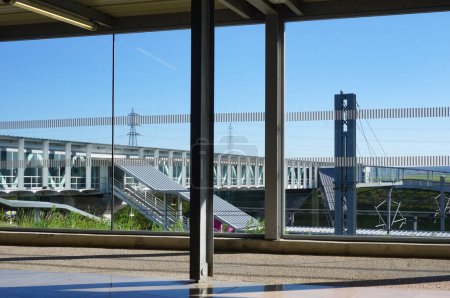 Foto de Bezannes, Francia - Abril 2021 - Puente peatonal de vidrio que cruza las vías de la estación de tren, visto desde el mirador de la sala de espera de la Gare de Champagne-Ardennes TGV, a pocos kilómetros de Reims - Imagen libre de derechos