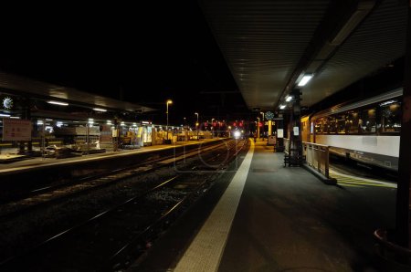 Photo for Toulouse, France - Aug. 2022 - Night view on the platforms of Toulouse-Matabiau Railway Station, main multimodal hub in Midi-Pyrenees ; afar, light-signalling and a train pulling into the station - Royalty Free Image
