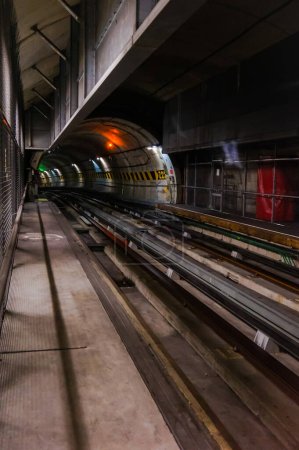 Foto de Toulouse, Francia - Nov. 2020 - túnel de hormigón subterráneo oscuro del metro automatizado de la ciudad operado por Tisso, en el tramo de doble vía de la línea, con señalización luminosa de ferrocarril rojo y verde - Imagen libre de derechos