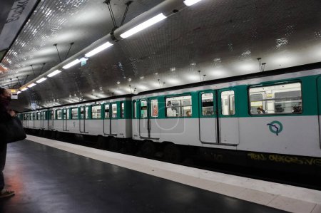 Foto de París, Francia - Abril 2022 - Un largo tren RATP blanco y verde sale de la plataforma de la estación de metro de Bercy, en el distrito 12, en la línea 6 de la red Ile-de-France Mobilits - Imagen libre de derechos