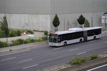 Photo for Toulouse, France - June 1, 2023 - A grey, articulated city bus, motion-burred, passes at high speed by B612 Building (Aerospace Valley headquarters), on the new Montaudran Innovation Campus - Royalty Free Image