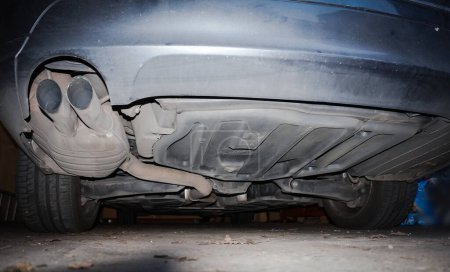 Foto de Vista inferior de la parte inferior de un coche ejecutivo alemán de gasóleo que muestra el tubo de escape conectado con un filtro de partículas o una olla catalítica y los brazos de suspensión para la suspensión de las ruedas - Imagen libre de derechos