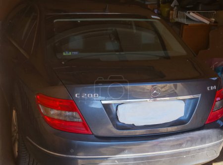 Photo for Albi, France - March 2020 - Premium German executive car sheltered in the shade in a garage ; rear view of a dark grey 2010-Mercedes C200 featuring a chrome bar on the trunk and a hidden number plate - Royalty Free Image
