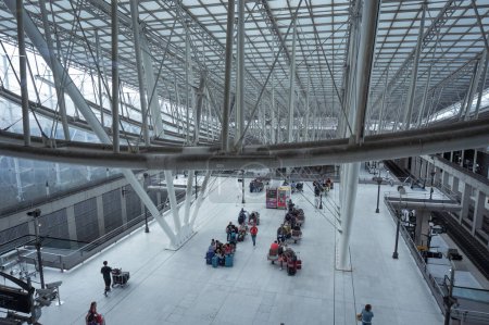 Téléchargez les photos : Aéroport Paris-Roissy-Charles de Gaulle, France - Juillet 2019 - Hall dans la gare, au-dessus de la plate-forme de la gare et des voies et sous un énorme cadre métallique, avec des passagers en attente - en image libre de droit