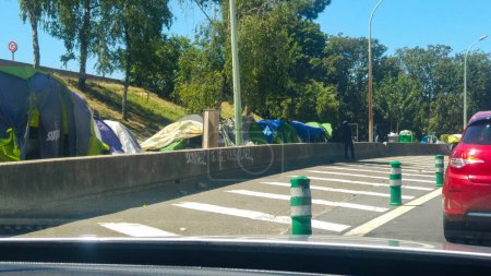 Photo for Paris, France - July 2019 - Clandestine immigrants' squatter settlement, as seen from the cars passing by the ring road, in Porte de la Chapelle, with tents illegally set up behind the crash barrier - Royalty Free Image