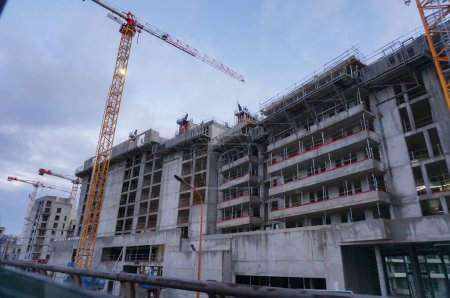 Photo for Hauts-de-Seine, France - Dec. 2020 - Worksite of large, concrete residential buildings, ordered by private real estate developers, under construction in the suburbs of Paris, using tower cranes - Royalty Free Image