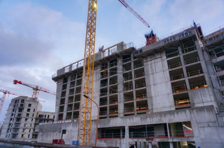 Foto de Hauts-de-Seine, Francia - Dic. 2020 - Grúas torre en el sitio de trabajo de grandes edificios residenciales de hormigón, ordenados por promotores inmobiliarios privados, en construcción en los suburbios de París - Imagen libre de derechos