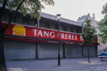 Foto de París, Francia - abril 2022 - Uno de los supermercados de la conocida cadena laosiano-china "Tang Frres" (hermanos Tang), en la avenida Choisy, con persiana enrollable aún cerrada a primera hora de la mañana - Imagen libre de derechos