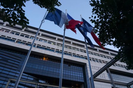Téléchargez les photos : Paris, France - Sept. 2020 - Vue de nuit à angle bas des drapeaux français et européens agitant devant le siège du ministère de l "Économie et des Finances, dans le quartier moderne de Bercy - en image libre de droit