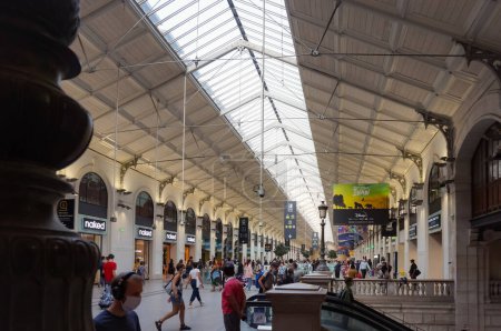 Foto de París, Francia - Sept. 2020 - Perspectiva de la claraboya de cristal de una larga sala llena de pasajeros y bordeada de tiendas bajo las arcadas, dentro de la estación de tren SNCF de Gare Saint-Lazare - Imagen libre de derechos