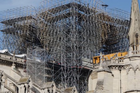 Foto de Los enormes andamios colocados en el techo de la catedral de Notre Dame en París, Francia, para apoyar la aguja para las obras de restauración, con rastros del colapso y el fuego que quemaron todo el marco de madera - Imagen libre de derechos