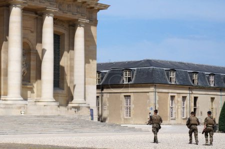Photo for Paris, France - July 2019 - Three French soldiers of the Operation Sentinelle (Vigipirate) patrolling in front of Dome des Invalides and the military hospital, and a police officer in the backround - Royalty Free Image