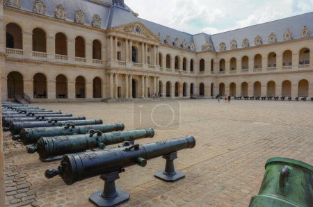 Photo for Paris, France - July 2019 - Ancient canons and artillery from the French army in the courtyard of the classical-architectural-style Hotel des Invalides, and the passeways behind the archs (Army Museum) - Royalty Free Image