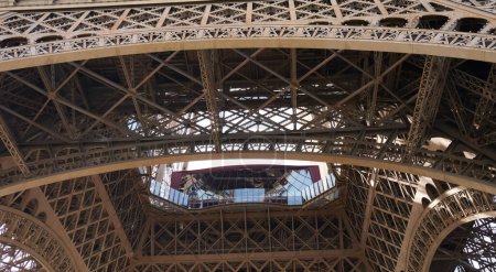 Foto de París, Francia - Vista de bajo ángulo del primer piso de la Torre Eiffel, al pie del monumento diseñado por el ingeniero francés Gustave Eiffel para la Exposición Internacional de París de 1889 - Imagen libre de derechos