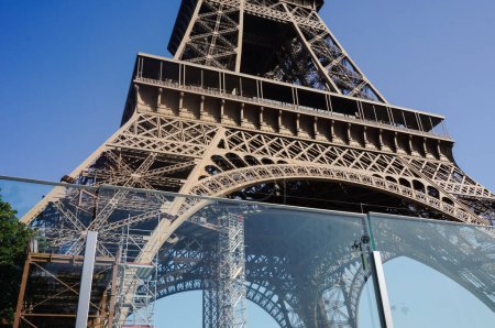 Foto de Low angle view of the first floor of the iconic Eiffel Tower in France, featuring the controversial bulletproof glass wall installed in 2018 after the terror attacks led by the Islamic State in Paris - Imagen libre de derechos
