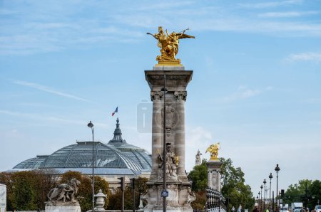 Foto de París, Francia - Sept. 2022 - Cubierta de cristal del Grand Palais (Gran Palacio) a lo lejos; en primera línea, coronada con una escultura dorada, una de las columnas del Puente Alexandre-III, en el distrito 8 - Imagen libre de derechos
