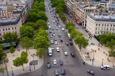 Foto de París, Francia - Julio 2019 - Vista de alto ángulo sobre la arbolada Avenida de la Grande Armee, con tráfico de coches, personas en las aceras y un coche de la Policía Nacional, disparado desde la parte superior del Arco del Triunfo - Imagen libre de derechos