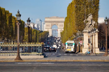 Photo for Paris, France - Nov. 2022 - Perspective view on the iconic Champs-Elyses Avenue, from Concorde Square up to the Triumph Arch ; the street, traffic-congested, is lined with trees pruned in cubes - Royalty Free Image