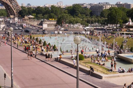 Photo for Paris, France - June 2019 - Crowded surroundings of the Eiffel Tower and Iena Bridge ; Parisians and tourists in swimsuit bathing under the waterjets of the fountain of Trocadero during the heat wave - Royalty Free Image