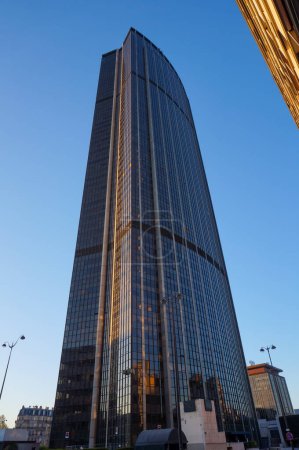Foto de París, Francia - abril 2021 - Vista de bajo ángulo al atardecer de la torre Montparnasse de 210 metros de altura, un rascacielos de cristal y un centro de negocios construido en la década de 1970 en el distrito 15 de la capital - Imagen libre de derechos