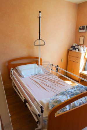 Photo for Occitanie, France - May 2020 - Medical supply for home care : an old person's room equipped with a mechanized hospital bed featuring lateral guardrails and a trapeze left to help the patient to get up - Royalty Free Image