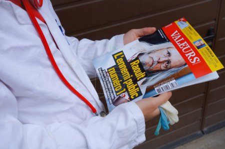 Téléchargez les photos : Marseille, France - Mai 2020 - Un médecin en chemisier blanc tient un journal mettant en vedette le Pr Didier Raoult, chercheur connu pour le traitement anti-Covid à l'hydroxychloroquine-azythromycine (photo mise en scène) - en image libre de droit