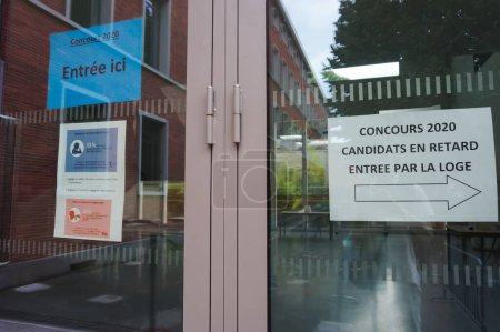 Foto de Toulouse, Francia - Julio 2020 - Paneles informativos e instrucciones de salud detrás de puertas de vidrio en la entrada del centro de escritura Lycee Pierre de Fermat, durante los exámenes competitivos de las escuelas de ingeniería - Imagen libre de derechos
