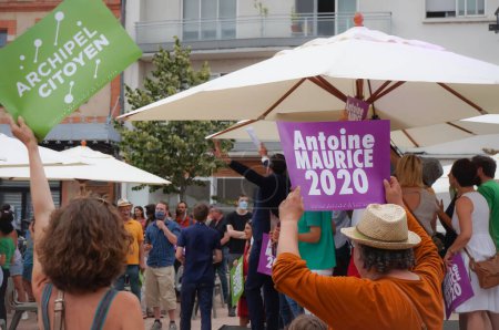 Téléchargez les photos : Toulouse, France - Le 25 juin 2020 - Des militants enthousiastes saluent joyeusement les signes électoraux tandis qu'Antoine Maurice, candidat écologiste d'Archipel Citoyen, salue ses partisans lors d'un rassemblement en plein air - en image libre de droit