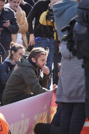 Foto de París, Francia - Nov. 2022 - Paul Larrouturu, famoso periodista socialista del canal de televisión LCI, se arrodilla para entrevistar a un activista en una manifestación de extrema izquierda frente a la Asamblea Nacional - Imagen libre de derechos