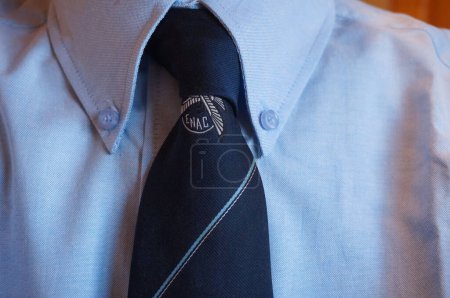 Foto de Toulouse, Francia - Agosto de 2021 - Detalle de una corbata azul oscuro de la Escuela Nacional de Aviación Civil de Francia (ENAC), cuyo logo representa un águila, que lleva puesta una camisa azul claro con botones de cuello - Imagen libre de derechos