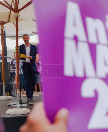 Foto de Toulouse, Francia - 25 de junio de 2020 - Mientras un partidario ondea un cartel electoral a su nombre, Antoine Maurice, candidato de Archipel Citoyen para alcalde de Toulouse, salta al escenario en un mitin al aire libre - Imagen libre de derechos