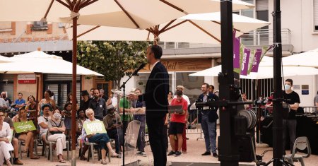 Foto de Toulouse, Francia - 25 de junio de 2020 - Antoine Maurice, candidato ecologista de Archipel Citoyen para alcalde, de pie detrás del micrófono de un púlpito de vidrio, da un discurso en una reunión electoral al aire libre - Imagen libre de derechos