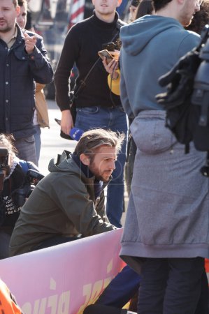 Foto de París, Francia - Nov. 2022 - Paul Larrouturu, famoso periodista socialista del canal de televisión LCI, se arrodilla para entrevistar a un activista en una manifestación de extrema izquierda frente a la Asamblea Nacional - Imagen libre de derechos