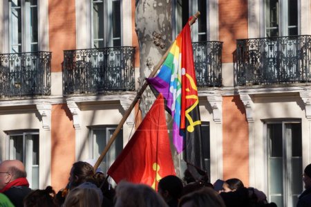 Foto de Toulouse, Francia - Feb. 2023 - Una bandera de la región de Occitanie, adornada con arcoíris, colores LGBTQIAA, ondeando en una manifestación dirigida por partidos de extrema izquierda y sindicatos contra la reforma de las pensiones del gobierno - Imagen libre de derechos