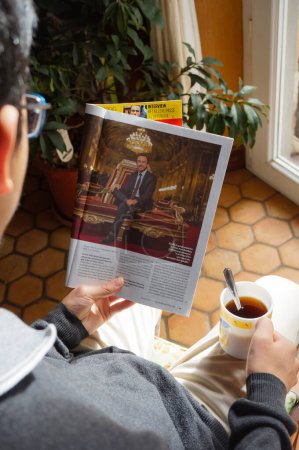 Photo for Paris, France - Aug. 2020 - A man reads Bruno Retailleau's interview in the newspaper Valeurs Actuelles while having a cup of tea ; Senator Retailleau of Vendee is a presidential candidate for 2022 - Royalty Free Image