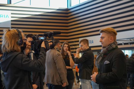 Photo for Reims, France - Feb. 5, 2022 - Among young supporters of Marine Le Pen, Rassemblement national's candidate for the presidential election, a young man on camera is interviewed by a female journalist - Royalty Free Image