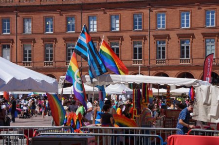 Foto de Toulouse, Francia - 10 de junio de 2023 - Mercado al aire libre a los pies de casas históricas de ladrillo en la Plaza Capitole, con banderas LGBT coloridas y con arco iris durante el Orgullo Gay ("Marche des Fierts" en francés)) - Imagen libre de derechos