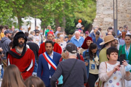 Foto de Reims, Francia - 28 de mayo de 2022 - Entre la multitud, Arnaud Robinet, alcalde de Reims, vestido con una faja tricolor oficial y acompañado por un actor que interpreta a un heraldo real, llega a las "Johanniques Fetes" - Imagen libre de derechos