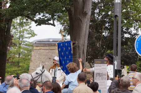 Foto de Reims, Francia - 28 de mayo de 2022 - Llegada a Saint-Remi de Juana de Arco, en un caballo blanco, con la bandera real, en el 2022 "Fetes johanniques", un festival tradicional alrededor del cuento de Juana de Arco - Imagen libre de derechos