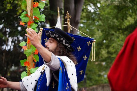 Téléchargez les photos : Reims, France - 28 mai 2022 - L'acteur incarnant le roi Charles VII, vêtu d'un manteau bleu, lève la main pour saluer la foule, à 2022 "Fetes johanniques", un festival qui célèbre le conte de Jeanne d'Arc - en image libre de droit