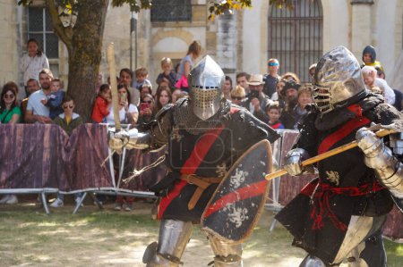 Foto de Reims, Francia - 29 de mayo de 2022 - Artistas en armadura de batalla, con espadas, hachas y escudos, reconstituyen un duelo de caballeros medievales, en las "Johanniques Fetes" de 2022, que celebran el cuento de Juana de Arco - Imagen libre de derechos