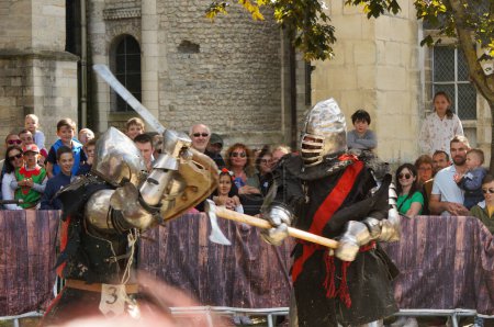 Foto de Reims, Francia - Mayo 2022 - Motion blurred photo featuring two knights in armor, attacking each other with a sword and an axe, at the 2022 "Fetes johanniques", which celebrate Joan of Arc 's tale - Imagen libre de derechos