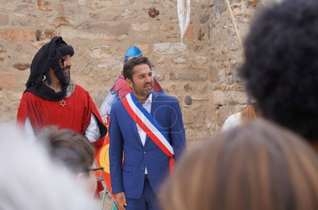 Téléchargez les photos : Reims, France - Mai 2022 - Vêtu d'une ceinture tricolore officielle, le maire de Reims assiste à un concours historique au milieu des "Fetes johanniques", avec un comédien habillé en rouge jouant un échevin médiéval - en image libre de droit