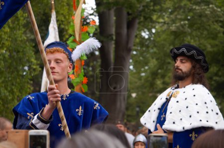 Foto de Reims, Francia - 28 de mayo de 2022 - Un heraldo medieval, por delante del rey Carlos VII de Francia, llevando su escudo de armas y un abrigo azul con la "flor de lis" real, en el 2022 "Fetes Johanniques" - Imagen libre de derechos