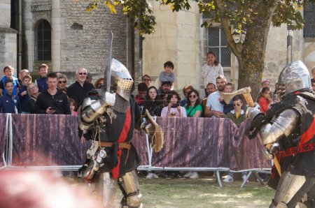 Foto de Reims, Francia - 29 de mayo de 2022 - Los actores en armadura de batalla reconstituyen un duelo de caballeros medievales, con espadas, hachas y escudos, en las "Johanniques Fetes" de 2022, que celebran el cuento de Juana de Arco. - Imagen libre de derechos