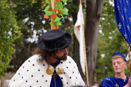 Téléchargez les photos : Reims, France - 28 mai 2022 - Le comédien barbu se faisant passer pour le roi Charles VII de France, vêtu d'un manteau de couronnement avec un collier d'hermine, s'incline pour saluer la foule, aux Fetes johanniques de 2022" - en image libre de droit