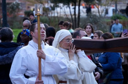 Foto de Toulouse, Francia - Marzo 2023 - Una joven hermana católica lleva una cruz, mientras que un monje sostiene una vela, ambas en sotanas blancas, en una marcha de paz organizada por los maronitas libaneses en el Día de Los Ángeles (Anunciación)) - Imagen libre de derechos