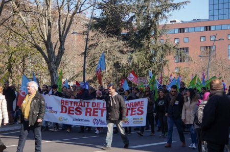 Foto de Toulouse, Francia - febrero de 2023 - Manifestantes marchan en oposición a la reforma de las pensiones, desplegando una pancarta y ondeando banderas de partidos de izquierda, en medio de protestas a nivel nacional contra el gobierno - Imagen libre de derechos