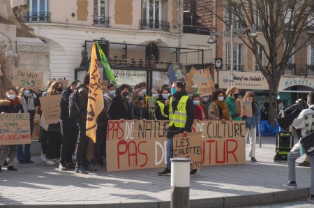 Photo for Reims, France - March 2021 - Young activists with flags and signboards, block the tramway tracks on Rue de Vesle, during a demonstration of students against climate change and global warming - Royalty Free Image